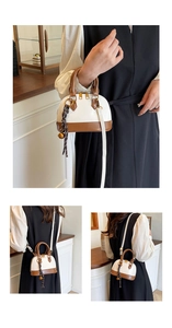 Detail view of mini shell bag showing gold zippers, woven charm, and adjustable strap