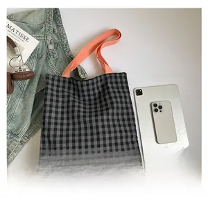 Vue détaillée du sac cabas à carreaux avec anses orange, tablette et casque audio