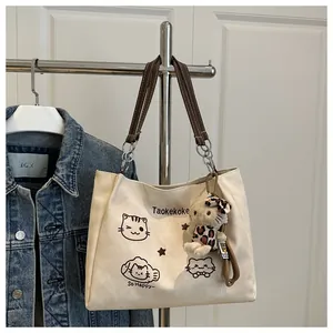 Detail of off-white canvas tote with cartoon cat prints and leopard plush charm
