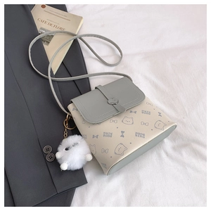 Detail of elegant small square bag with heart lock and white pompom charm accessory