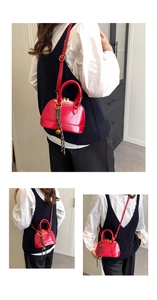 Detail of red shell-shaped crossbody bag featuring woven rope and gold metal ball charms