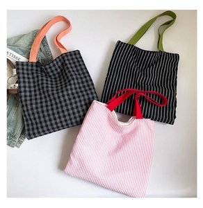 Détail à plat de sacs fourre-tout en toile à carreaux et rayures avec anses colorées
