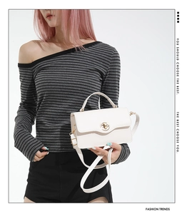 Détail du sac bandoulière en cuir blanc avec fermoir doré porté par un mannequin