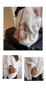 Detail view of brown vintage shell crossbody bag with gold zippers and woven strap
