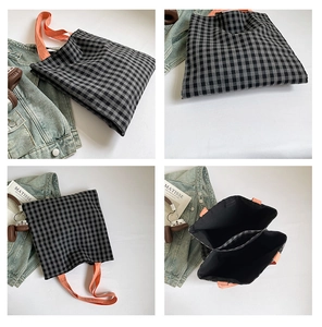 Detail of checkered canvas tote bag with orange handles and internal compartment view