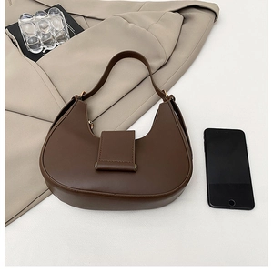 Detailed view of deep brown crescent hobo bag with gold clasp on a beige blazer
