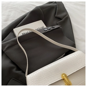Detail of white crocodile pattern shoulder bag with a polished gold metallic buckle
