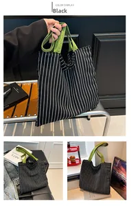 Detail of canvas tote bag with black vertical stripes and green handles for daily use