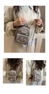 Detail of light gray canvas mini backpack with cute cartoon embroidery and gold chain strap