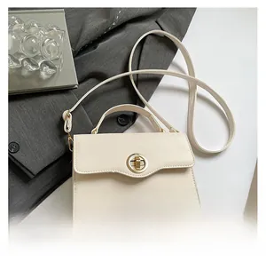 Détail du sac crème avec rabat ondulé et fermoir rotatif doré sur fond de costume