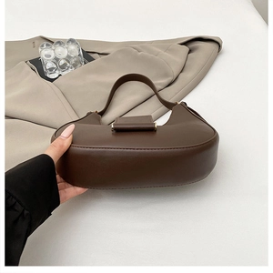 Close-up of brown crescent handbag with smooth leather texture and gold buckle detail