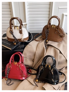 Detail showing various glossy shell-shaped handbags with golden zippers and bell pendants