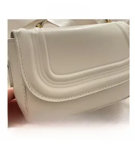 Gros plan du sac bandoulière blanc avec coutures en U triples et boucle dorée