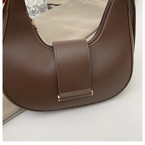 Detailed close-up of brown crescent underarm bag showing gold hardware and leather texture