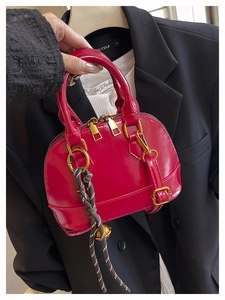Close-up of bright magenta shell-shaped handbag with glossy finish and gold metal zipper