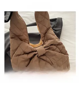 Detailansicht der braunen gesteppten Handtasche in Schleifenform mit Rautenmuster