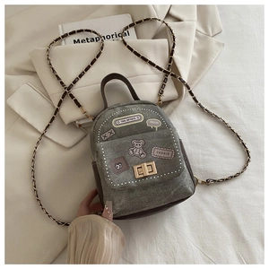 Close-up of grey denim mini bag with cute bear embroidery and chain strap detail