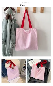 Detail of pink and white striped canvas tote bag with vibrant red handles and soft texture