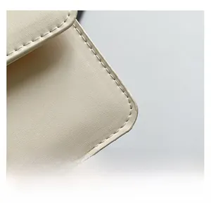 Gros plan sur la texture du cuir beige et les coutures précises du sac à main carré