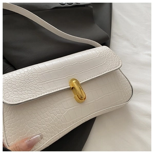 Close-up of white croc-embossed leather underarm bag with a shiny gold metal buckle