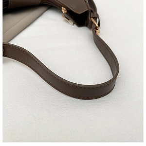 Close-up of brown leather shoulder bag strap with gold zipper and stitching detail