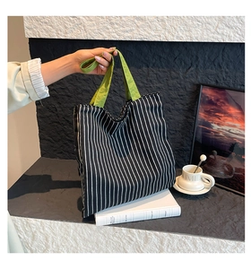 Détail du sac cabas en toile rayée avec anses vertes sur fond de style minimaliste chic