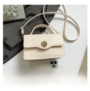 Détail macro du sac bandoulière blanc crème avec fermoir rotatif doré sophistiqué