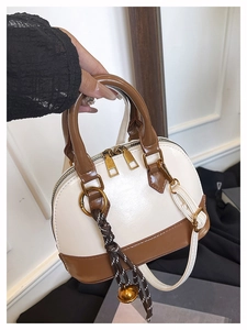 Détail du sac à main bicolore avec double fermeture éclair dorée et pendentif décoratif
