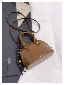 Brown shell-shaped crossbody bag on a gray suit with stylish scarf detail and gold hardware