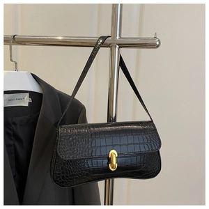Detailed view of the black crocodile pattern texture and golden metal buckle on handbag