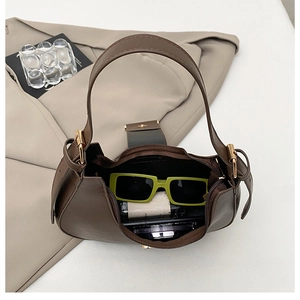 Top view of brown crescent shoulder bag showing internal capacity with sunglasses