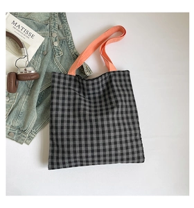 Vue de dessus d'un sac cabas à carreaux avec anses orange et accessoires de style