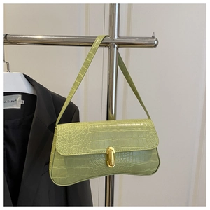 Detail of light green crocodile embossed leather shoulder bag with gold cylindrical clasp