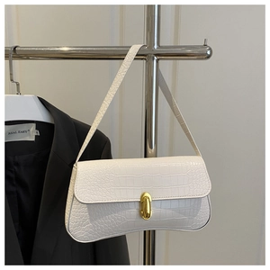 Detailed view of white crocodile pattern shoulder bag with gold clasp on a rack