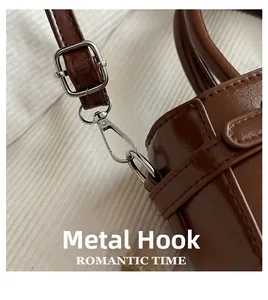 Close-up of polished silver hardware hooks and stitching on brown leather bucket bag