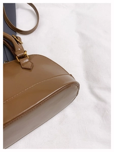 Détail du sac à main marron brillant avec coutures serrées et boucle dorée