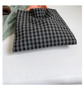 Détail d'un grand sac cabas à carreaux gris avec des poignées orange vif en toile