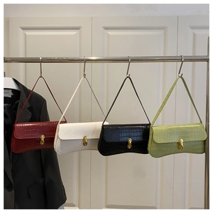 Détail de quatre sacs sous les bras en cuir de crocodile en rouge, blanc, noir et vert