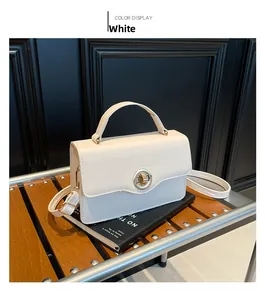 Detail of a white leather handbag with golden round swivel lock on a wooden bench