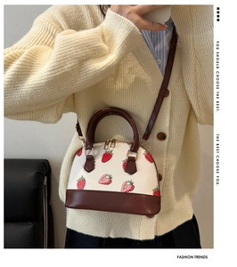 Détail du sac coquille imprimé fraises avec poignées marron et fermeture à double zip