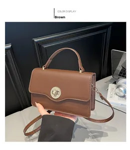 Detail of a brown leather handbag with a circular metal twist lock and a modern minimalist vibe