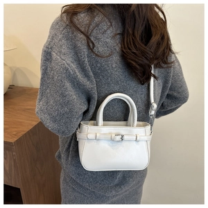 Detailed view of a white leather bucket bag featuring adjustable straps and dual top handles