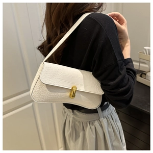 Close-up of white crocodile texture faux leather and golden metal twist lock on the bag