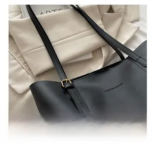 Detailed view of adjustable golden buckle and premium leather texture on a black tote bag