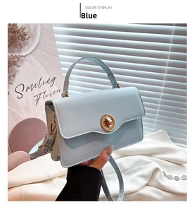Close-up of light blue leather handbag with round metal twist lock and shoulder strap hooks