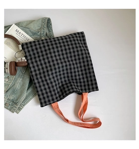 Détail du cabas en toile à carreaux avec anses orange et accessoires de style artistique