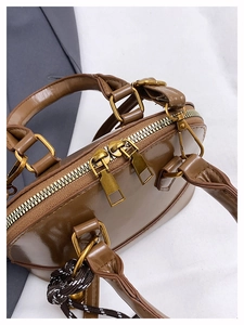 Détail du sac coquillage marron avec doubles zips dorés et ornement de poignée