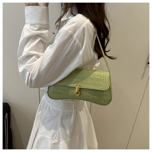 Detail of light green faux crocodile skin baguette bag with a gold metal buckle