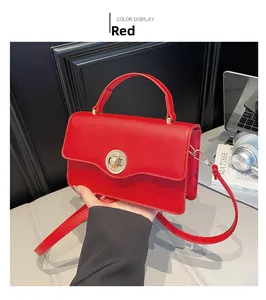 Close-up of red leather square bag with golden circular twist lock and top handle