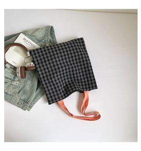 Détail d'un sac cabas à carreaux avec poignée orange et texture en toile durable